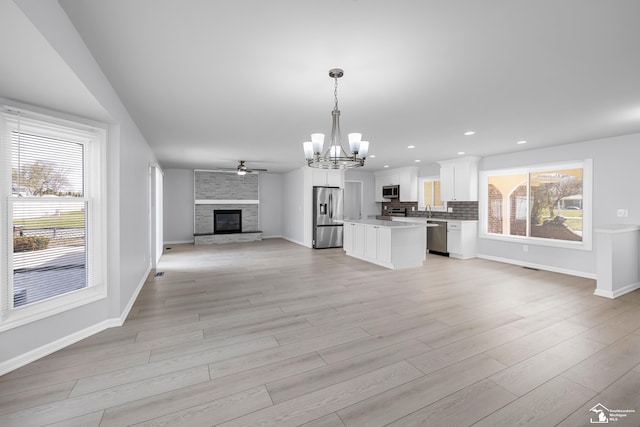 unfurnished living room with plenty of natural light, light wood-type flooring, and baseboards
