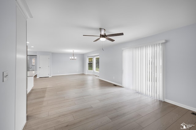 empty room featuring baseboards, recessed lighting, light wood-style floors, visible vents, and ceiling fan with notable chandelier