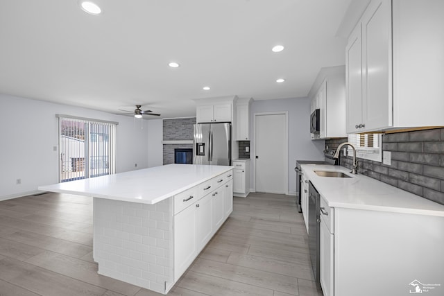 kitchen featuring ceiling fan, tasteful backsplash, a kitchen island, appliances with stainless steel finishes, and a sink