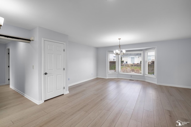 unfurnished room with baseboards, light wood-type flooring, and a notable chandelier