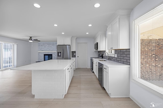 kitchen with white cabinets, open floor plan, appliances with stainless steel finishes, a ceiling fan, and a kitchen island
