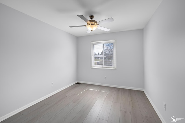 spare room with wood finished floors, ceiling fan, and baseboards