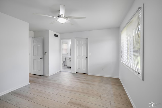 unfurnished bedroom featuring ceiling fan, connected bathroom, light wood-style flooring, visible vents, and baseboards