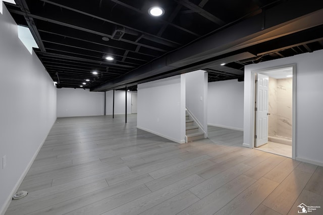 finished basement with stairs, baseboards, and wood finished floors