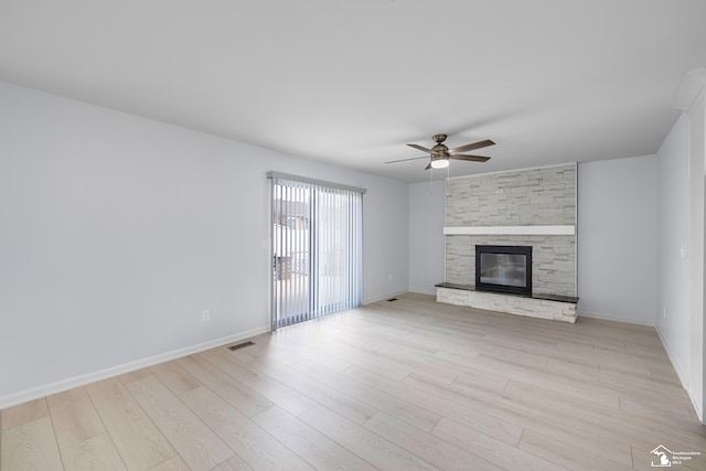 unfurnished living room featuring a stone fireplace, ceiling fan, light wood-type flooring, and baseboards