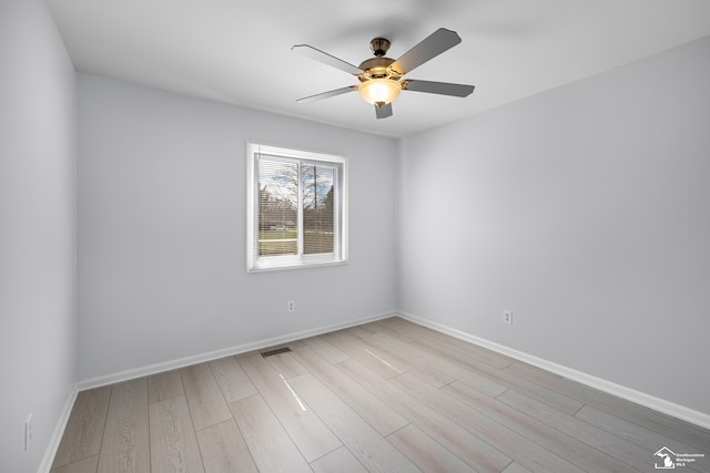 spare room with wood finished floors, ceiling fan, baseboards, and visible vents