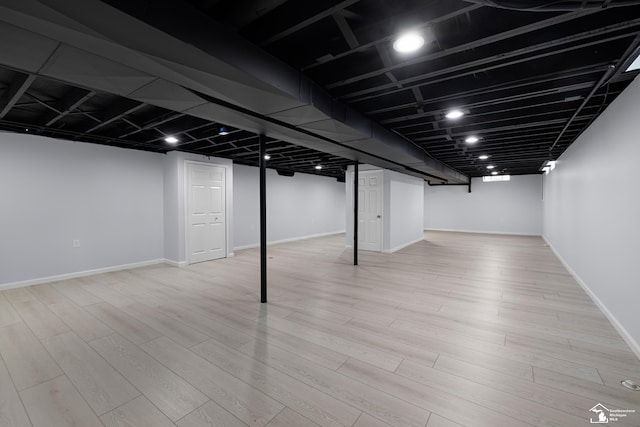 finished basement featuring light wood-type flooring and baseboards