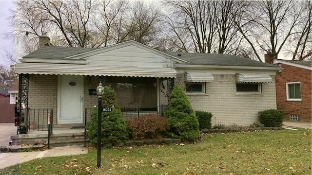 8021 Trafalgar St, Taylor, MI 48180 - view of front of property featuring brick siding, a porch, a front lawn, and a chimney