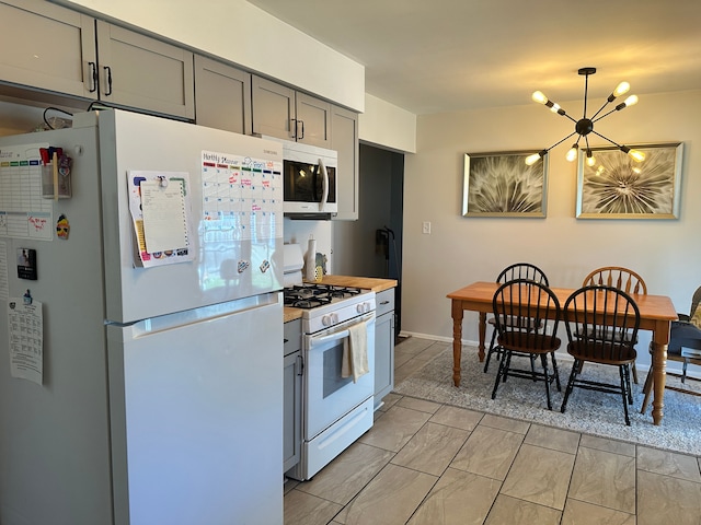 kitchen featuring a chandelier, white appliances, light countertops, gray cabinetry, and hanging light fixtures