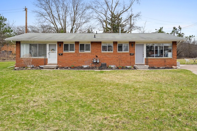 single story home with entry steps, a front lawn, and brick siding
