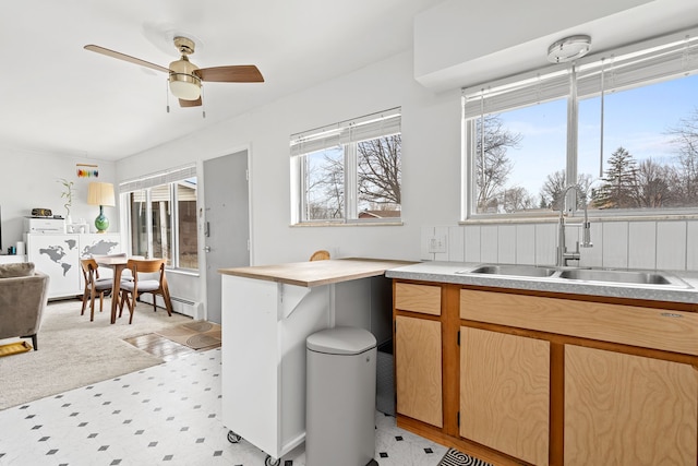 interior space featuring light countertops, ceiling fan, a sink, and light floors