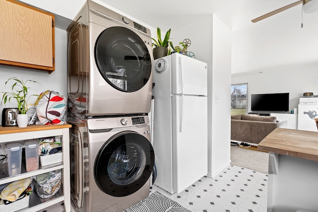laundry area featuring a ceiling fan, light floors, and stacked washer and clothes dryer