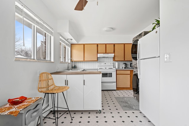 kitchen featuring a sink, white appliances, a peninsula, under cabinet range hood, and light floors