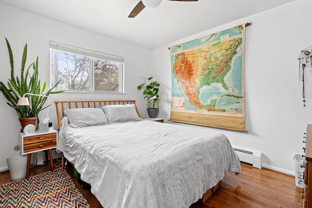 bedroom featuring baseboard heating, baseboards, ornamental molding, ceiling fan, and wood finished floors