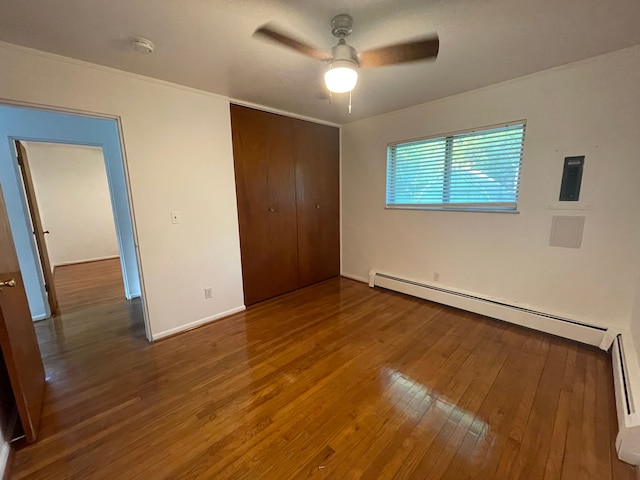 unfurnished bedroom with a closet, baseboards, a baseboard radiator, ceiling fan, and hardwood / wood-style flooring