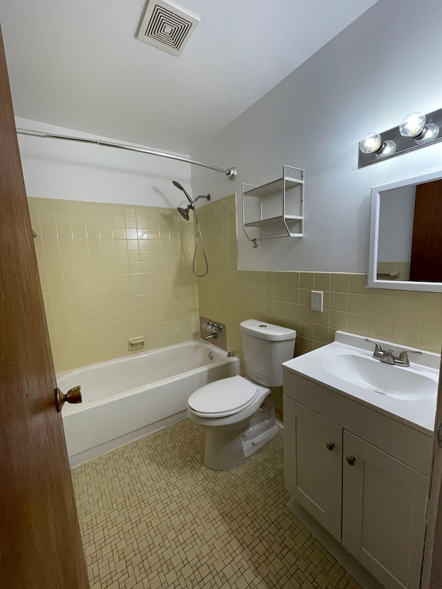 bathroom featuring vanity, bathing tub / shower combination, toilet, visible vents, and tile walls