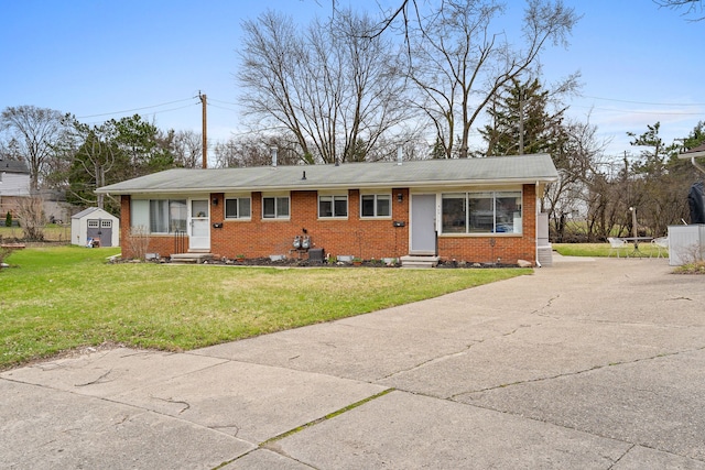 ranch-style house with entry steps, an outbuilding, a front yard, and brick siding