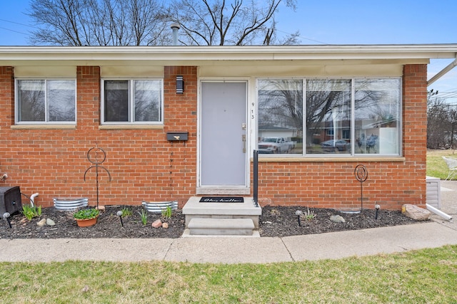 property entrance with crawl space, central air condition unit, and brick siding