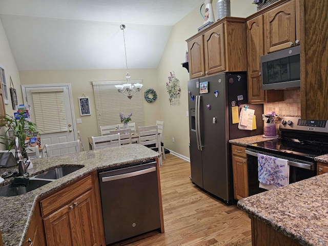 kitchen with a notable chandelier, a sink, stainless steel appliances, light wood-type flooring, and vaulted ceiling