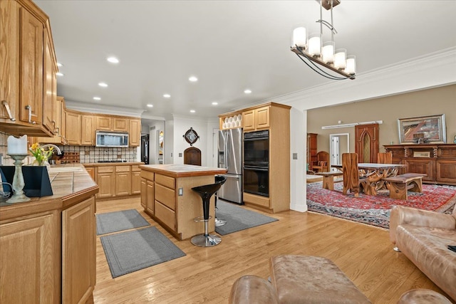 kitchen featuring tile countertops, ornamental molding, and appliances with stainless steel finishes