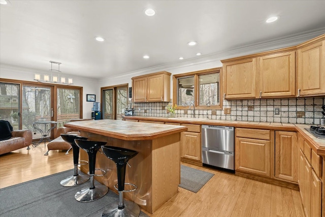 kitchen featuring tile counters, stainless steel appliances, a breakfast bar, and light wood-style flooring