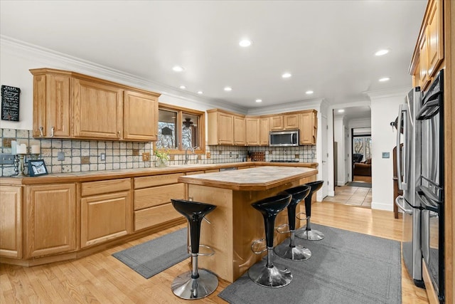 kitchen featuring a kitchen bar, a center island, ornamental molding, and stainless steel appliances