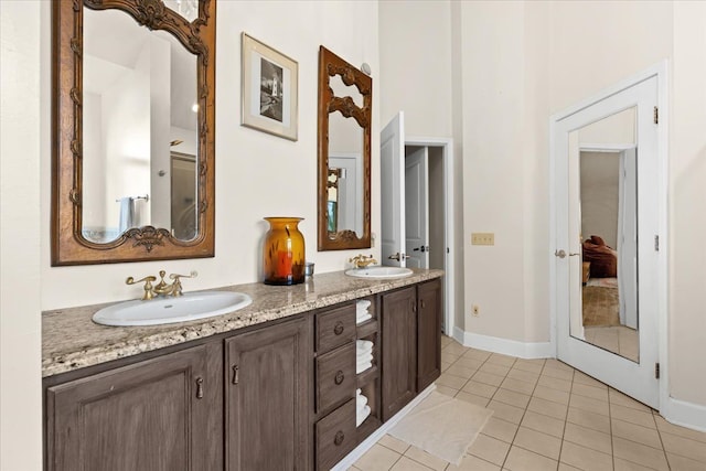 full bathroom featuring double vanity, tile patterned flooring, baseboards, and a sink