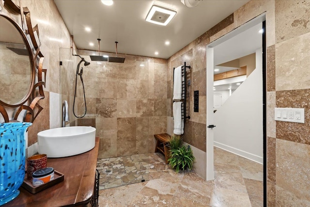 bathroom with stone finish floor, tile walls, vanity, and a walk in shower