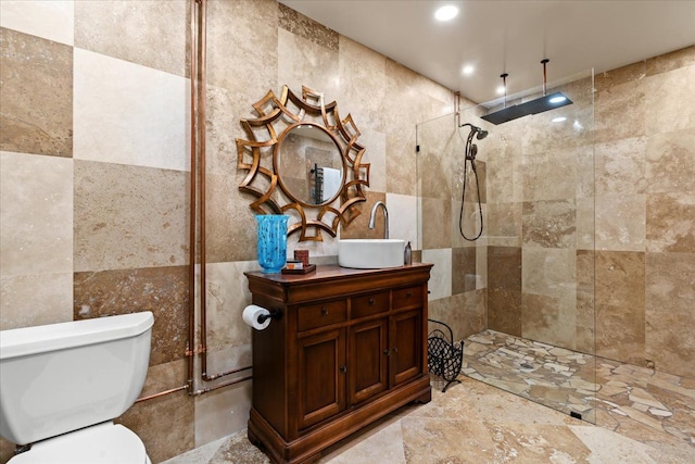 bathroom featuring vanity, tile walls, toilet, a walk in shower, and recessed lighting