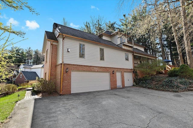 view of home's exterior featuring brick siding, aphalt driveway, and an attached garage