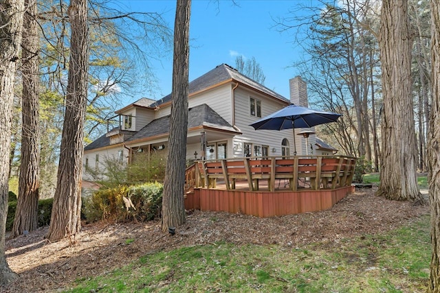 rear view of property featuring a chimney and a wooden deck