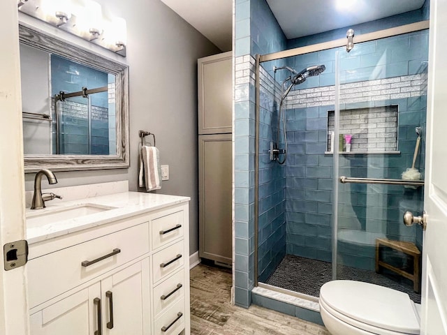 full bathroom with a shower stall, wood finished floors, vanity, and toilet