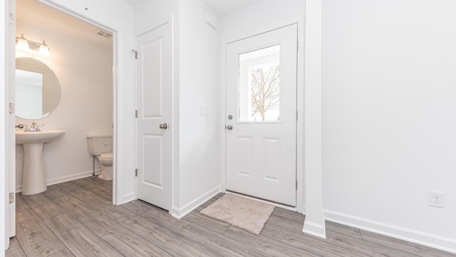 entryway with baseboards, visible vents, and light wood finished floors