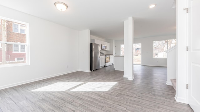 unfurnished living room with light wood-type flooring and baseboards