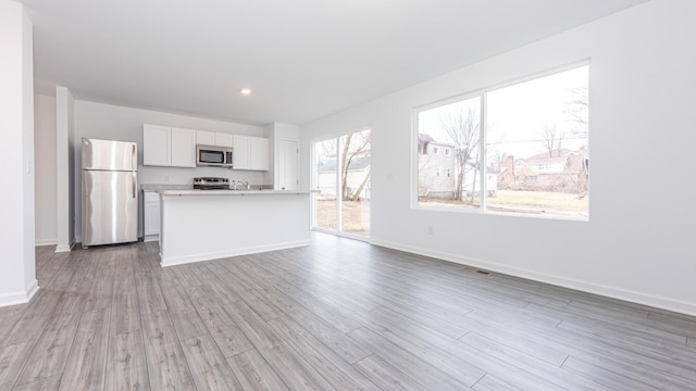 unfurnished living room with wood finished floors, baseboards, and recessed lighting