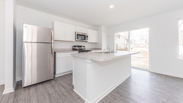 kitchen with appliances with stainless steel finishes, a sink, white cabinetry, and light countertops