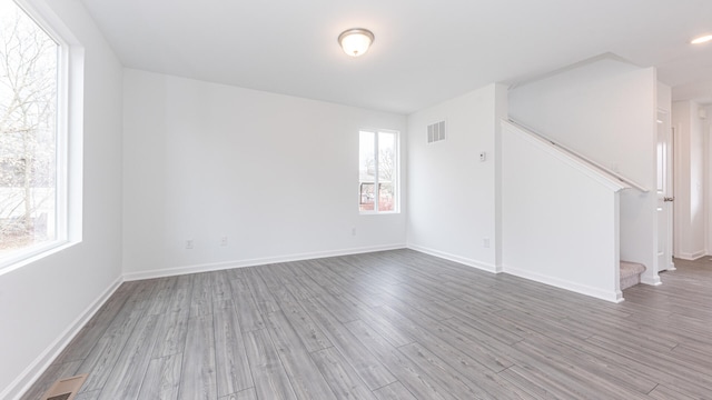 unfurnished room with stairway, visible vents, baseboards, and wood finished floors