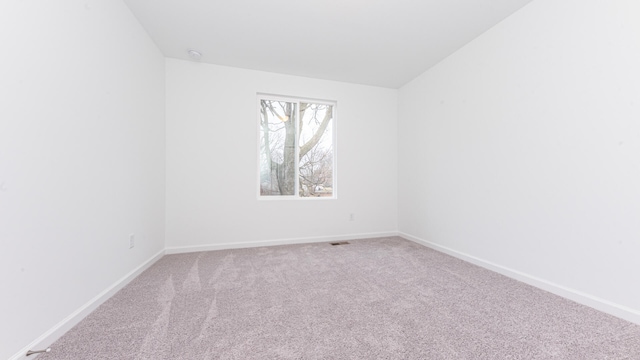 carpeted empty room with baseboards, vaulted ceiling, and visible vents