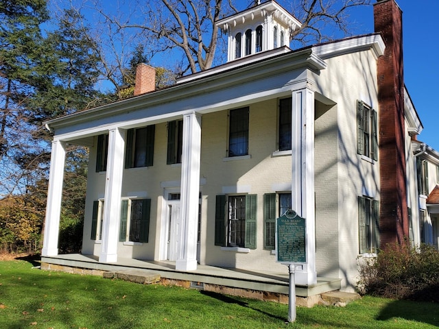 back of house with a porch, a chimney, and a yard