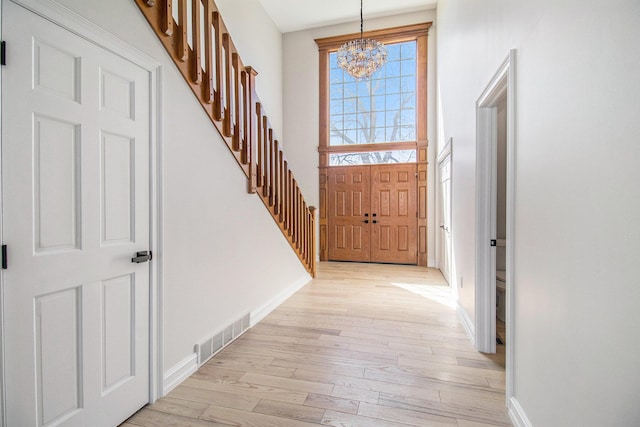 6376 Sterling Dr, Newport, MI 48166 - entrance foyer with visible vents, baseboards, a chandelier, light wood-style floors, and stairway