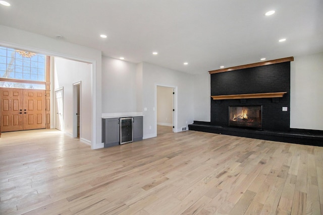 6376 Sterling Dr, Newport, MI 48166 - unfurnished living room with a fireplace, light wood-style flooring, recessed lighting, wine cooler, and baseboards