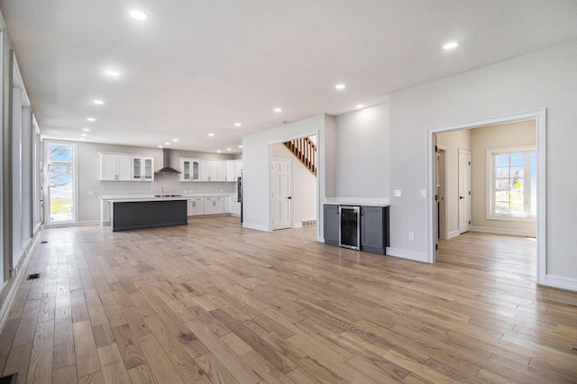 6376 Sterling Dr, Newport, MI 48166 - unfurnished living room with baseboards, wine cooler, stairway, recessed lighting, and light wood-style flooring