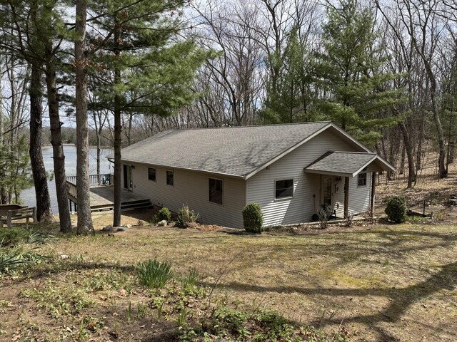 exterior space with a shingled roof and a water view