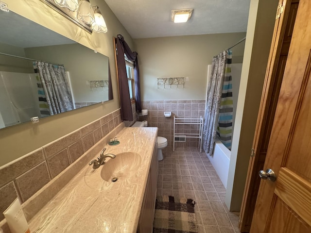 full bathroom with tile patterned flooring, wainscoting, toilet, tile walls, and shower / bathtub combination with curtain
