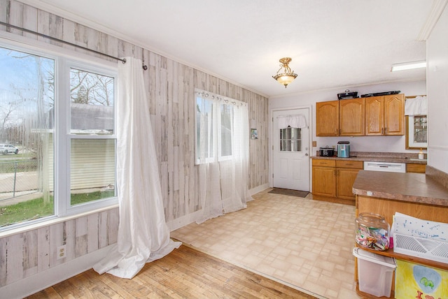 kitchen with a wealth of natural light, wood walls, dishwasher, and ornamental molding