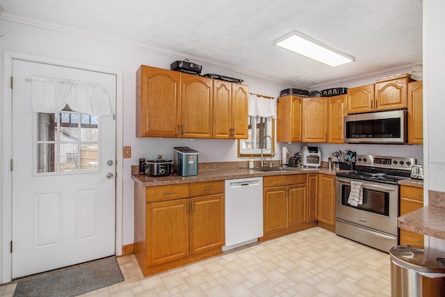 kitchen with brown cabinets, a sink, ornamental molding, and stainless steel appliances