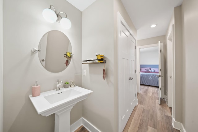 bathroom featuring wood finished floors, baseboards, and recessed lighting