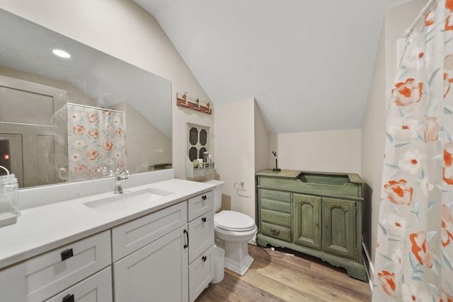 full bath with toilet, wood finished floors, vanity, and lofted ceiling
