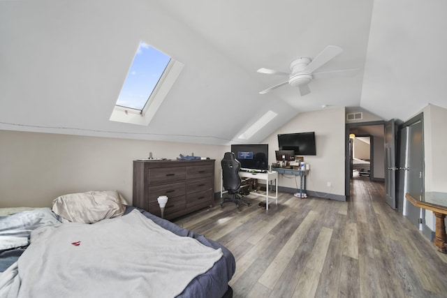 bedroom with vaulted ceiling with skylight, wood finished floors, a ceiling fan, and visible vents