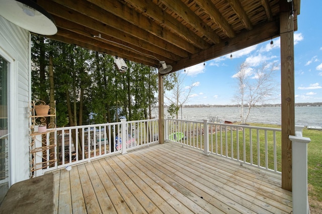 wooden terrace with a water view and a yard